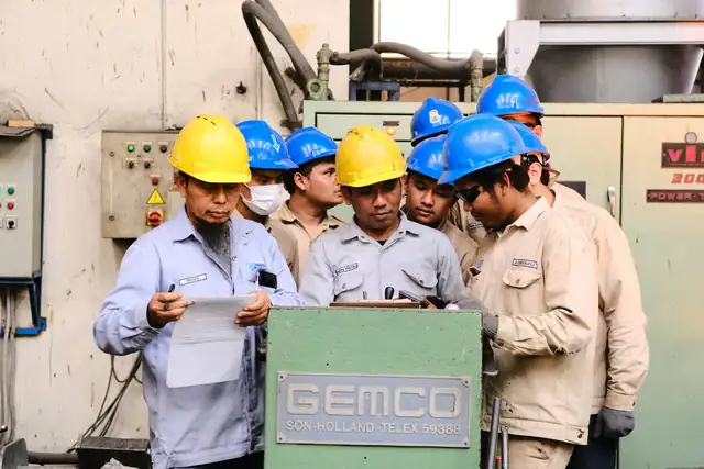 Grupo de supervisores con casco revisando documentos junto a un equipo industrial
